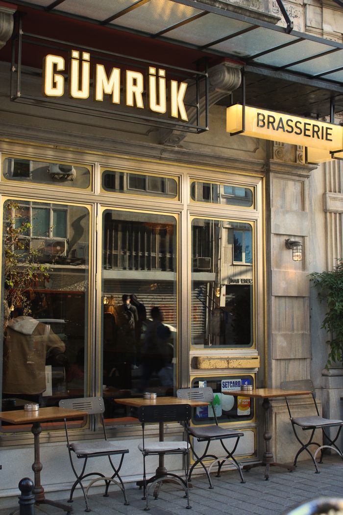 about-03 Outdoor café with quaint tables and chairs, framed by classic architecture.
